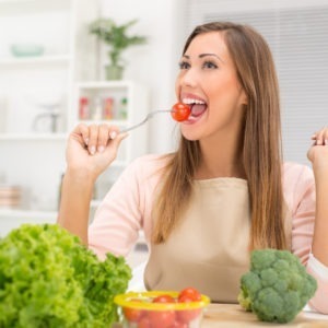 Kobieta uśmiecha się i je pomidora