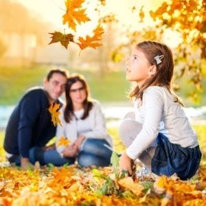 Dziewczynka i rodzice bawią się jesiennymi liśćmi